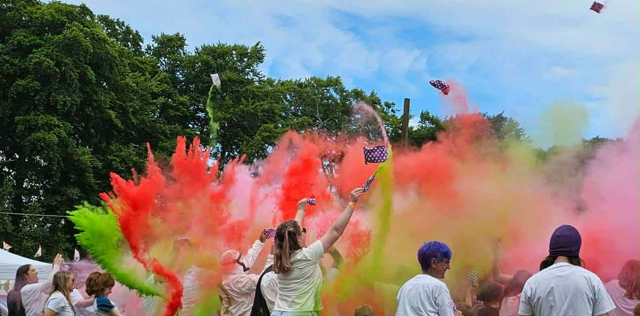 Festival crowd throwing bright coloured powder into the air at ReKINDle Festival.