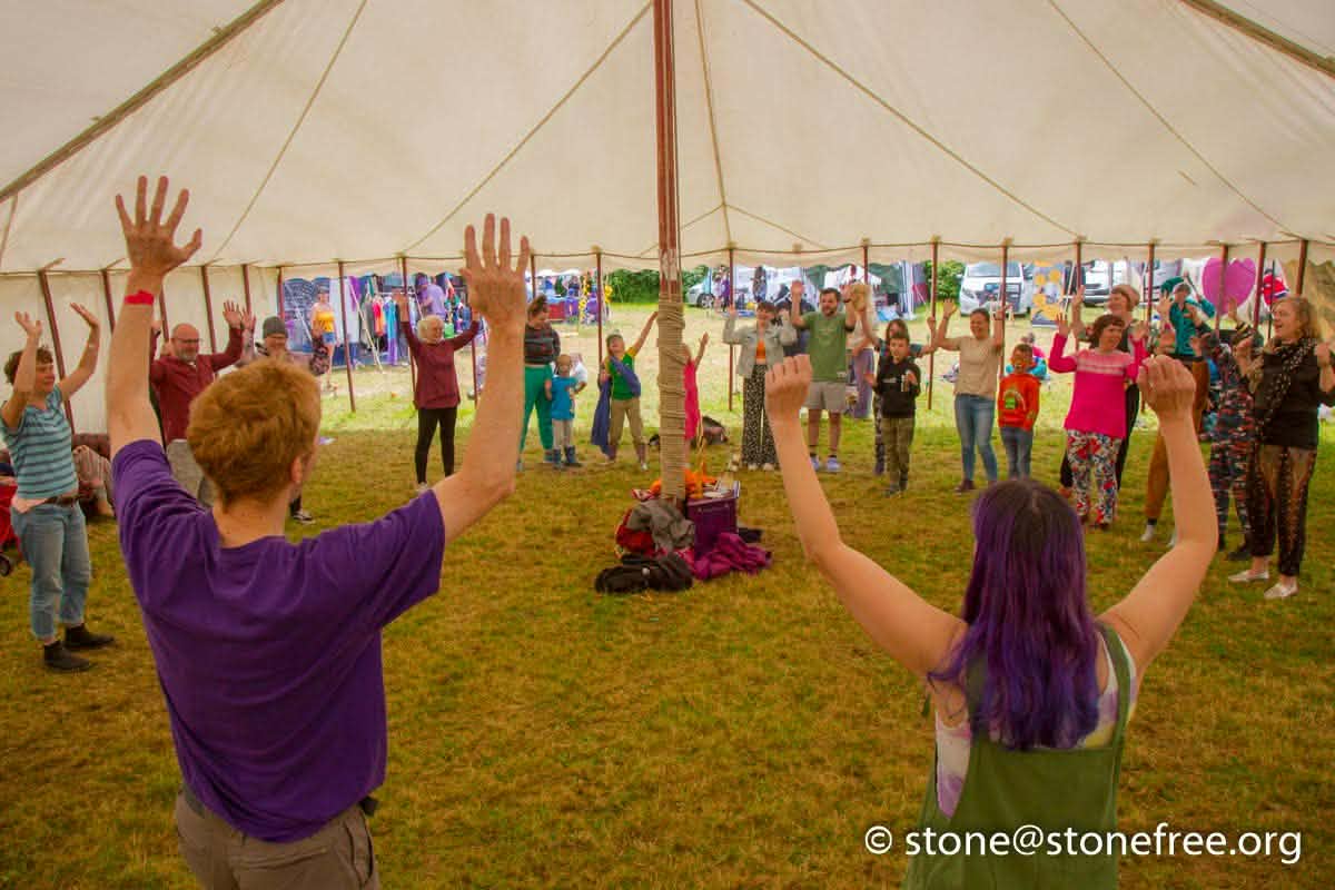 People joining a movement workshop inside a festival tent.