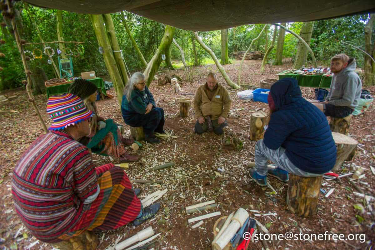 People sitting together in a woodland bush craft area.