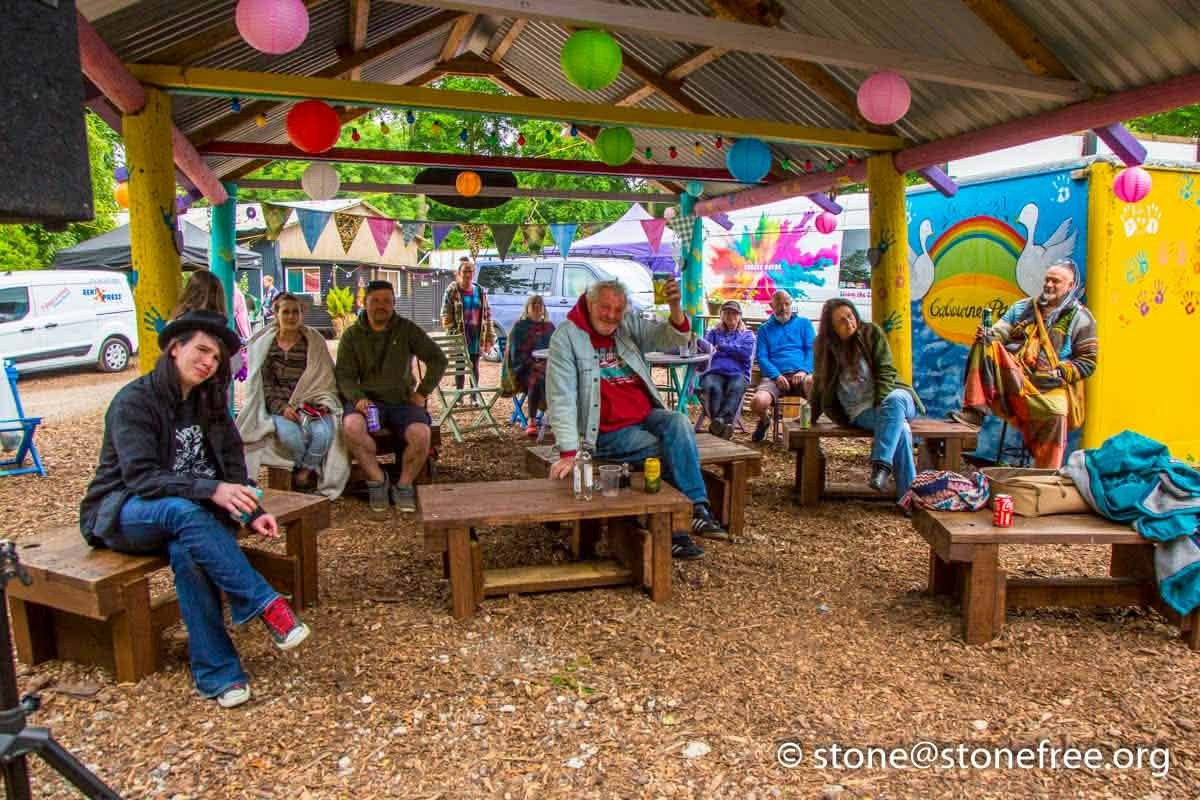 Covered festival cafe seating area with people gathered together.